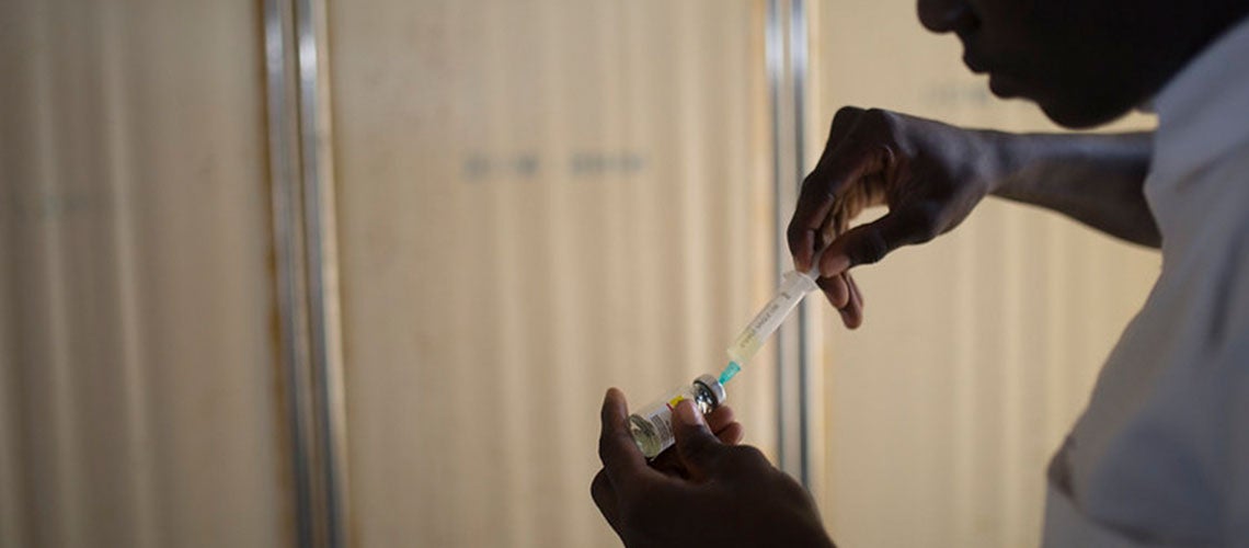 A man fills a syringe from a vial, Nigeria A man fills a syringe from a vial, Nigeria