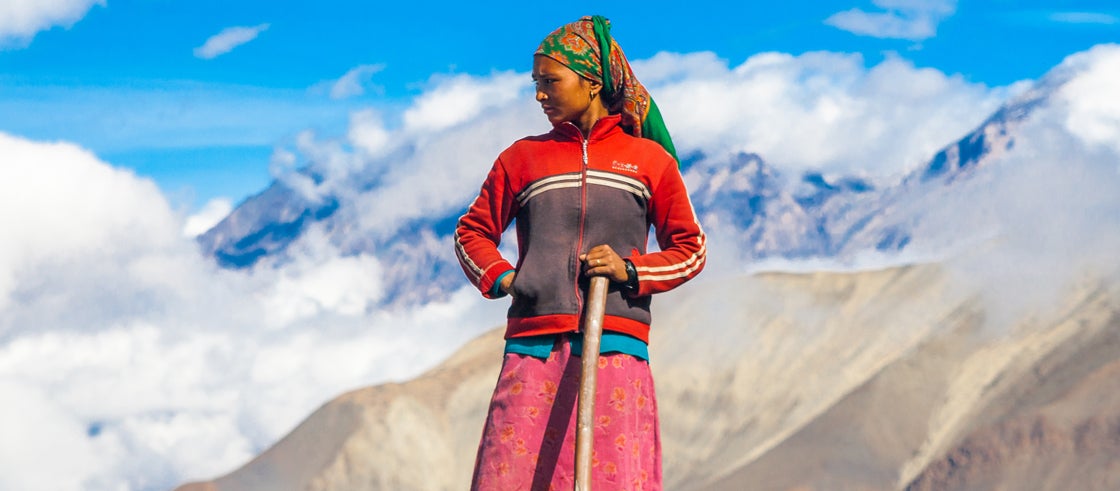 Local women is standing in the mountains holding a shovel. Local women is standing in the mountains holding a shovel.