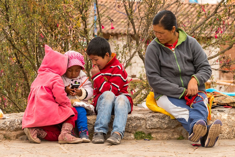 Woman sitting with her children playing with a phone in rural Peru. Credit: nmessana/iStock Woman sitting with her children playing with a phone in rural Peru. Credit: nmessana/iStock